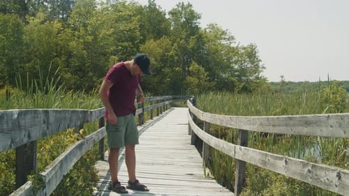 Man Spraying Mosquito Repellent By the Lake on a Sunny Day