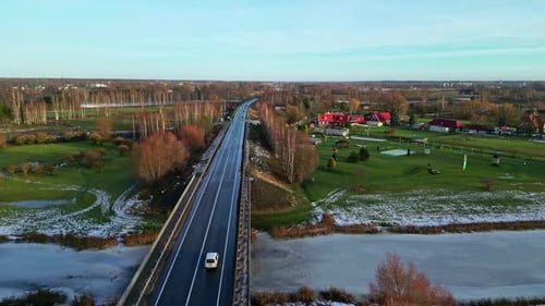 Cars driving on bridge over frozen river, aerial drone view
