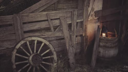 Rustic Wooden Barn Interior with Flickering Lantern and Wagon Wheel