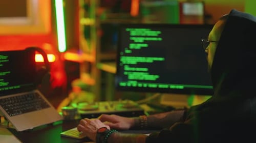 Un hacker écrit du code et un programmeur informatique dans un système Hoodie Cacks utilisant un ordinateur dans le noir
