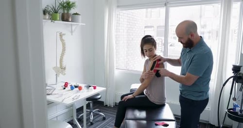 Physical Therapist Applies Kinesiology Tape to Patient Shoulder