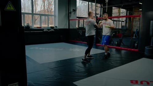 Sparringboxer üben im Fitnessstudio Schläge. Der Kampflehrer bringt Schläge für die Meisterschaft
bei