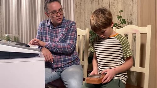 Woman Teaching Young Boy to Play Kalimba