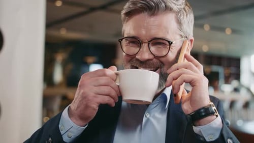 Man Speaking on Cellphone and Drinking Coffee
