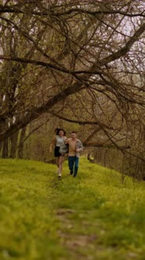 A young couple holding hands run through the forest, embodying an active lifestyle and tourism. Spor