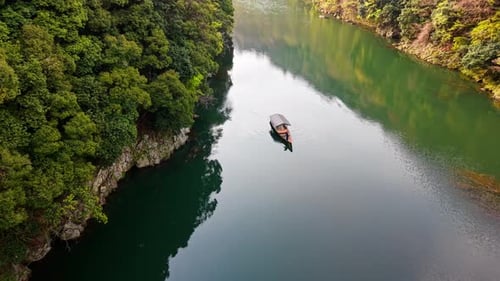 Drohnenaufnahme eines Bootes, das sich auf dem Katsura-Fluss in Arashiyama, Japan, bei Tageslicht bewegt