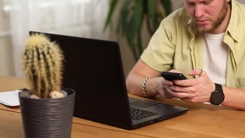 Businessman holding smartphone sitting in office, using cell phone mobile apps