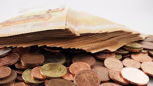 Close-up of rotating metal coins and banknotes. Rotating stack of euro banknotes and euro cents.