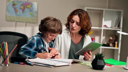 in the Children's Room a Schoolboy in a White Sweater and a Blue Checkered Shirt at Desk Does
