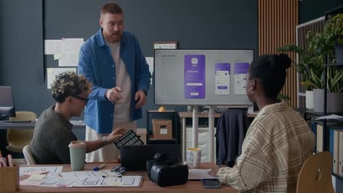 Mann präsentiert einem vielfältigen Team von Kollegen im Büro das UI-Design für mobile App