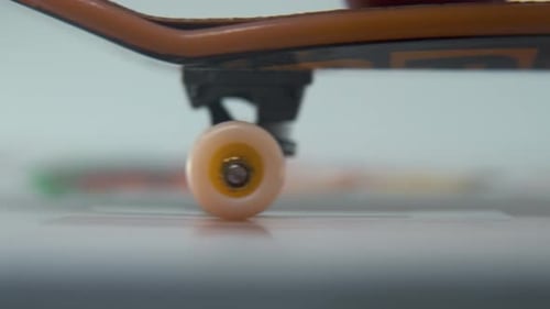 A hyper detailed shot of a mini skateboard, close-up on the tiny white wheels, riding fingerboard fr