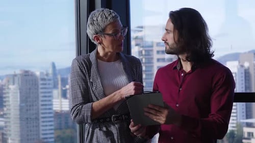 Businesspeople Discussing in Modern Office Using Tablet with City View in the Background