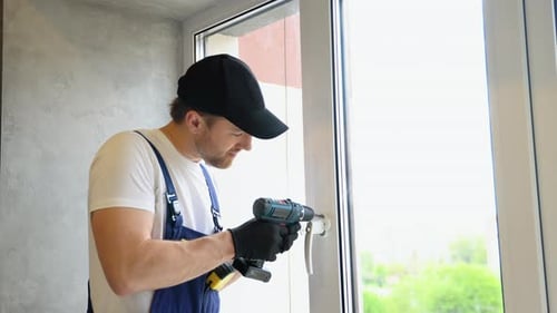 Worker in Overalls Installing a Window Lock for Hotel Room Safety The Concept of Protecting a Child