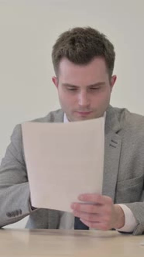 Man in Suit Reads Documents With Positive Reaction
