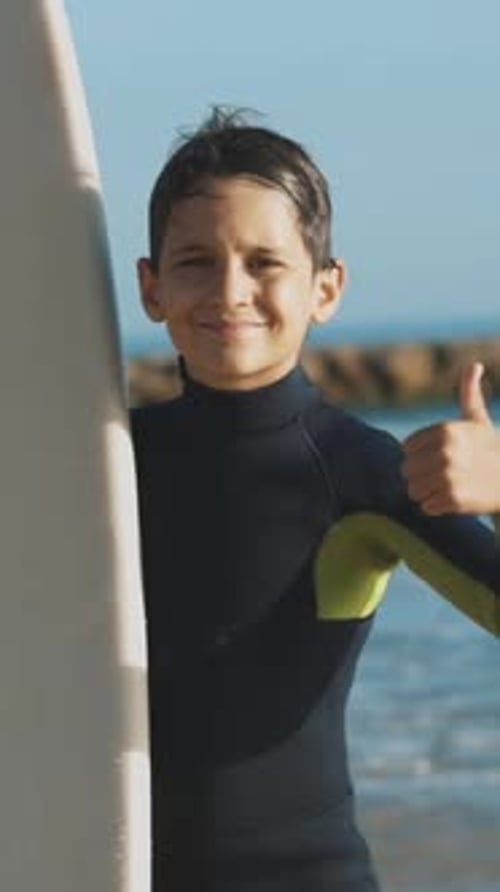 Young Boy Surfer Giving Thumbs Up at Beach