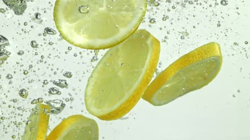 Lemon Slices Falling Into Water with Bubbles