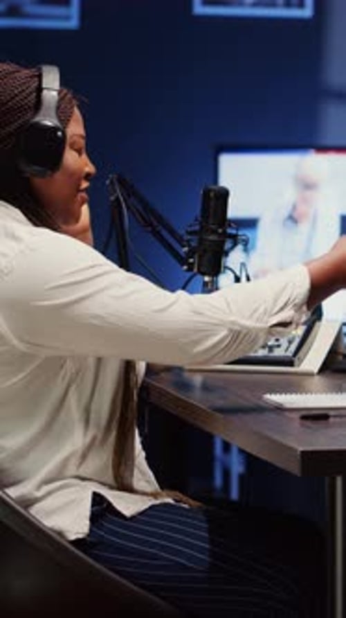 Vertical Video Woman on Podcast Adjusting Analog Mixer While Talking with Guest During Marathon