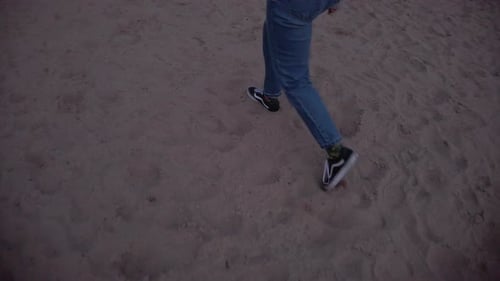 slow motion tracking shot of a girl walking on a sand beach