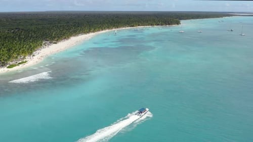 A powerboat cruises across tropical azure waters, the Dominican Republic, Aerial panorama reveal