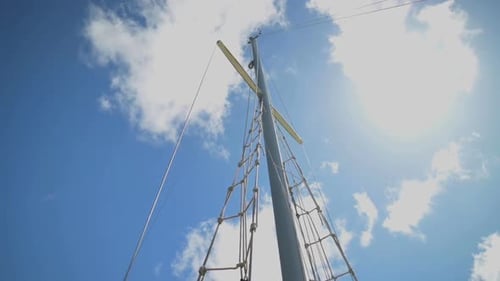 Ein Segelbootmast vor wunderschönem blauem Himmel mit Wolken - Aufnahme aus flachem Winkel