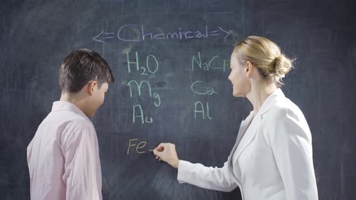 Student Learning Chemistry with Teacher at Chalkboard