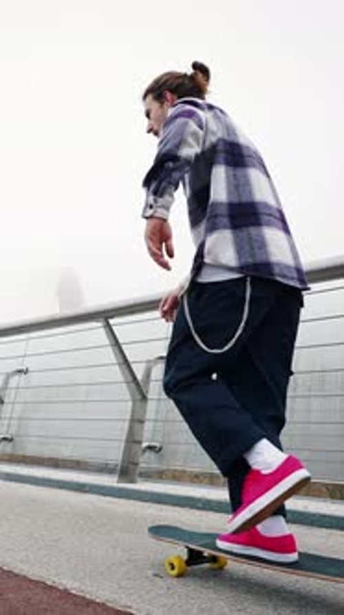 Close Portrait of Young Professional Skater Guy Performing Board Flip on City Bridge on Foggy