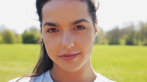 Smiling young woman in park setting close up
