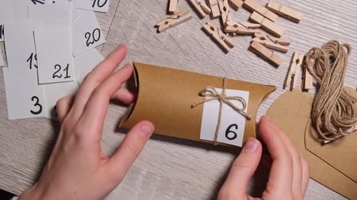 Unrecognizable Young Woman Sticks Number on Craft Bag Fastens with Clothespin
