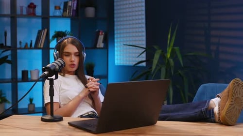 Woman is hosting radio podcast with microphone and laptop.