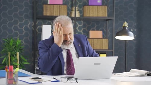 Frustrated Senior Man at Office Desk with Laptop