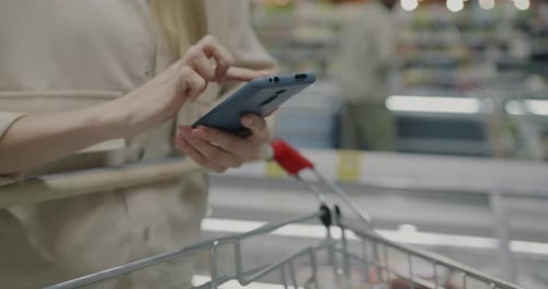 Woman Checks Phone While Grocery Shopping