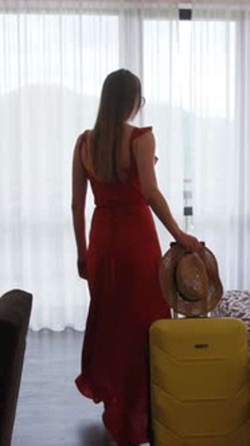 A Stylish Woman in a Red Dress Stands with Her Luggage Ready for Adventure in the City