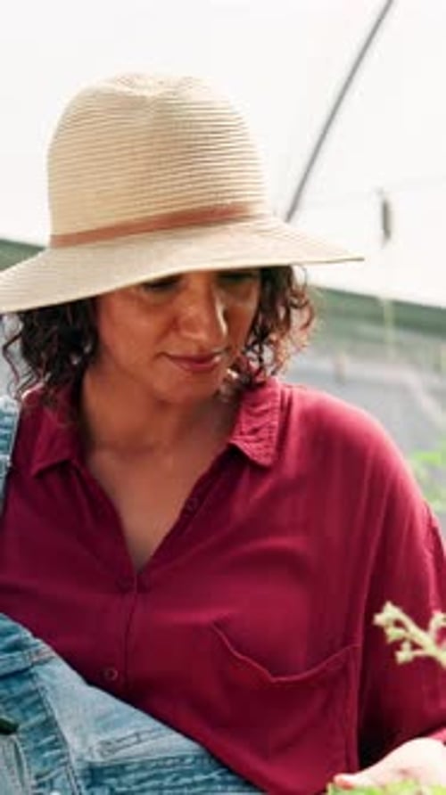 Woman Smiling and Holding Seedling in Greenhouse
