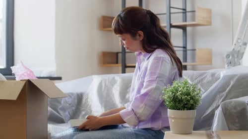 Woman Packing Photo Frame into Box in Living Room