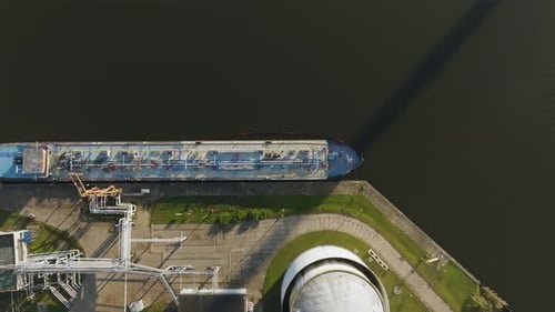 Aerial view of a large tanker vessel loading fuel at an oil terminal