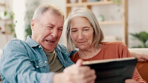 Senior Couple Laughing Together at Tablet in Home