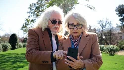 Senior Couple Using Smartphone in City Park