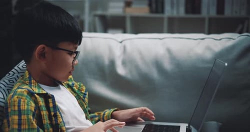 Garçon asiatique portant des lunettes écolier utilisant un ordinateur portable