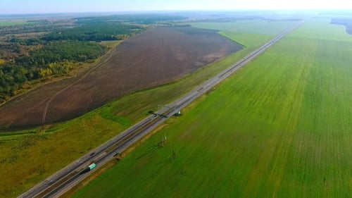 Sky View Cars Drive Along Highway Past Green Fields. Cars Highway On