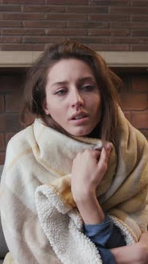 Brunette Woman Wrapped in Blanket Sits Inside