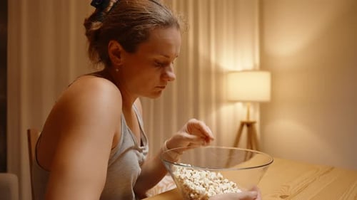 Woman Eating Popcorn at Table Indoors