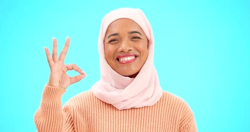 Muslimische Frau, ok, unterschreibe und lächle mit der Hand auf das Gesicht für Emoji, Symbol oder Vereinbarung