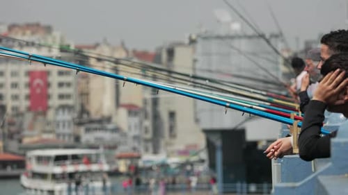 Angelruten reihen sich entlang der Istanbuler Küste aneinander, während Männer die Freizeitaktivität genießen