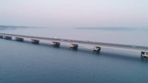 Drohnenaufnahme der Lowwater Bridge über die Bucht mit fahrendem Auto während des Sonnenuntergangs Aktiv