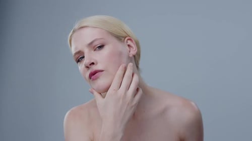 Sensual Young Woman Doing Facial Massage Routine for Healthy Glowing Skin Looking in the Mirror