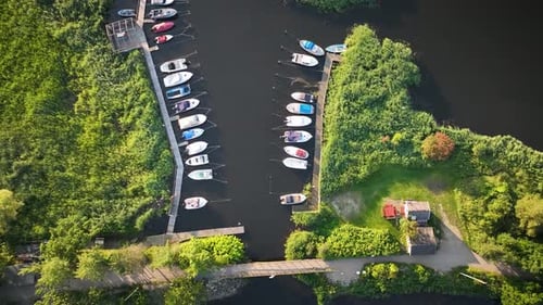 Aerial shot of marina with moored motorboats while camera tilts up and moves backward; sun rays refl