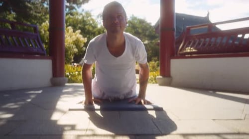 Caucasian adult male practices yoga. Surrounding ambience is that of a traditional Chinese temple wi