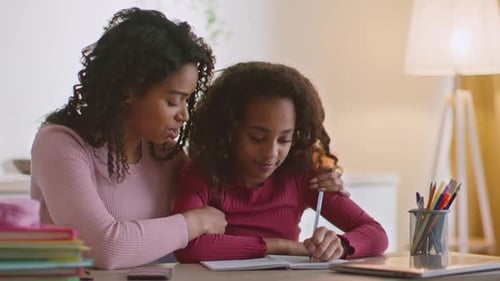 Smiling Woman Helping Girl with Homework Indoors