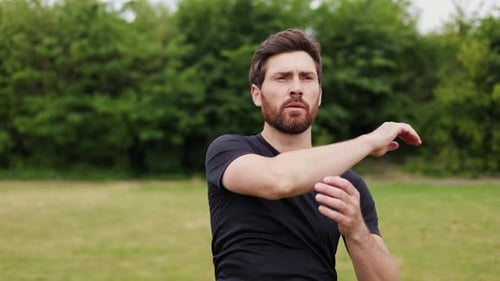 Concentrated Caucasian Man Doing Sports Exercise in Park or Green Outdoors Area