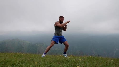 Athletic Man is Training and Fighting in Nature Handsome Sporty Man is Boxing Alone at Top of Mount